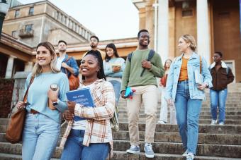 Diversity, students and walking on university steps, school stairs or college campus to morning class. Smile, happy people and bonding education friends in global scholarship opportunity or open day